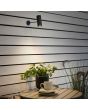 Sfeerfoto van Konstsmide Multi zwarte spot met wandhouder waarvan de spot oplaadbaar is met de USB kabel boven een tuintafel met plantenpot