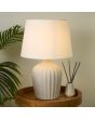 Searchlight Padstow EU66037CR sfeerfoto van tafellamp van 50cm hoog met geribbelde terrazzo voet in creme kleur met ivoor witte kap van textiel op een houten tafeltje naast een kamerplant
