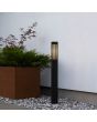 Sfeeerfoto van Konstsmide Pistoia mat zwarte paallamp van 95 cm hoog met acryl venster achter een raster langs een pad naast een plantenbak