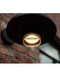 Sfeerfoto van onderaanzicht Lutec Plato mat zwarte wandlamp voor buiten van 24 cm breed met platte schijfvormige kap en LED unit naar beneden aan een buitenmuur