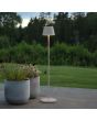 Sfeerfoto van Konstsmide Pomezia witte aluminium IP54 terraslamp van 124 cm hoog met rond kapje naast twee plantenpotten voor een vergezicht