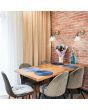 Searchlight Pyramid 1277AB sfeerfoto van twee antiek brons kleurige wandlampen met helder glazen kegelvormige kap en trekschakelaar aan een rood stenen muur boven een eettafel met vijf stoelen en vier blauwe placemats