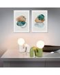 Sfeerfoto van een warm grijze en groene Reality Quinn warm grijze tafellamp van 21,5 cm hoog met N vormige lampvoet van keramiek met rond glazen lichtbol met een diameter van 10 cm op de N op een kastje onder twee schilderijen