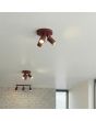 sfeerfoto van twee bordeauxrood metalen plafondspots met ronde plafondplaat van 20 cm in diameter en drie met staaf richtbare spotjes tegen een glad plafond
