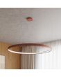 Sfeerfoto van een okerrode ringvormige hanglamp Rio met een LED ring aan de binnenzijde aan een betongrijs plafond
