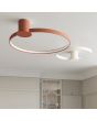 Sfeerfoto van een beige en een okerrode ringvormige plafondlamp Rio aan een strak gestukt plafond