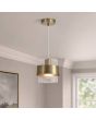 messing kleurige hanglamp van 18 cm in diameter met een geribbeld glazen kap en een messing band eromheen in een woonkamer
