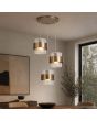 messing kleurige hanglamp met een diameter van 42 cm en drie pendels met elk een geribbeld glazen kap en een messing band eromheen boven een eettafel