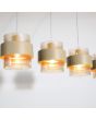 Detailfoto van de kappen van de Searchlight Royal hanglamp van 93cm lang met zandkleurige plafondbalk en vier pendels zandkleurige metalen band om een cilindervormig amberkleurig ribbelglazen kap