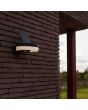 Sfeerfoto van Lutec Runda antraciet grijze schijfvormige wandlamp van 18 cm breed met kantelbaar zonnepaneel bovenop 