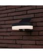 Sfeerfoto zijaanzicht van Lutec Runda antraciet grijze schijfvormige wandlamp van 18 cm breed met kantelbaar zonnepaneel bovenop 