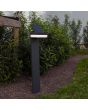 Sfeerfoto van Lutec Runda antraciet grijze sokkellamp van 74 cm hoog met schijfvormige lantaarn met kantelbaar zonnepaneel bovenop in een tuin