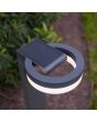 Sfeerfoto met bovenaanzicht van Lutec Runda antraciet grijze sokkellamp van 74 cm hoog met schijfvormige lantaarn met kantelbaar zonnepaneel bovenop in een tuin