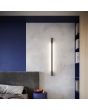 Thoro Sappo TH.207 sfeerfoto van zwarte slanke wandlamp van 150cm voor indirect licht tegen een betonnen deel van de muur in een slaapkamer