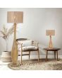 Trio Toba 567200130 sfeerfoto van houten tafellamp met kap van jute touwen naast een rieten stoel met een vloerlamp uit dezelfde serie