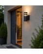 zwart geribbelde wandlamp voor buiten van 19 cm hoog met twee transparante ringen aan een muur naast de voordeur