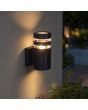 zwart geribbelde wandlamp voor buiten van 19 cm hoog met twee transparante ringen tegen een buitenmuur