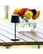 Sfeerfoto van Konstsmide Vence mini mat zwarte tafellamp voor buiten van 21 cm hoog met touchdimmer op de kop op een tuintafel met vaas met bloemen