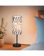 Sfeerfoto van de Reality Zebara tafellamp van 36 cm hoog met ronde kap van textiel met een zebra huid print op een houten nachtkastje naast een bed